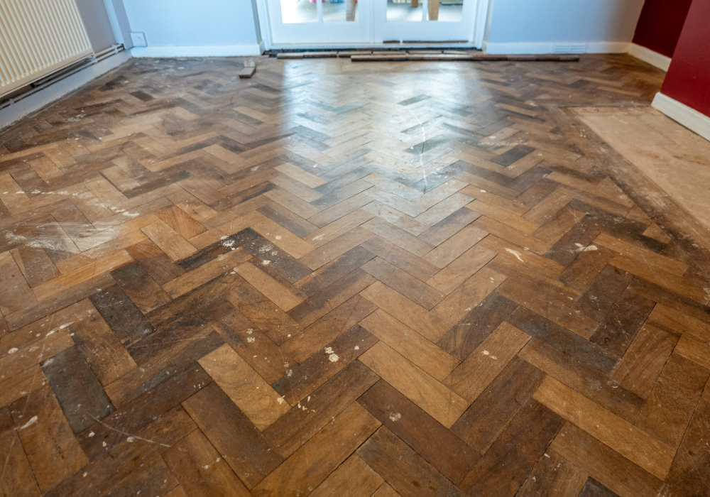 Parquet flooring with visible wear and tear, awaiting a professional touch